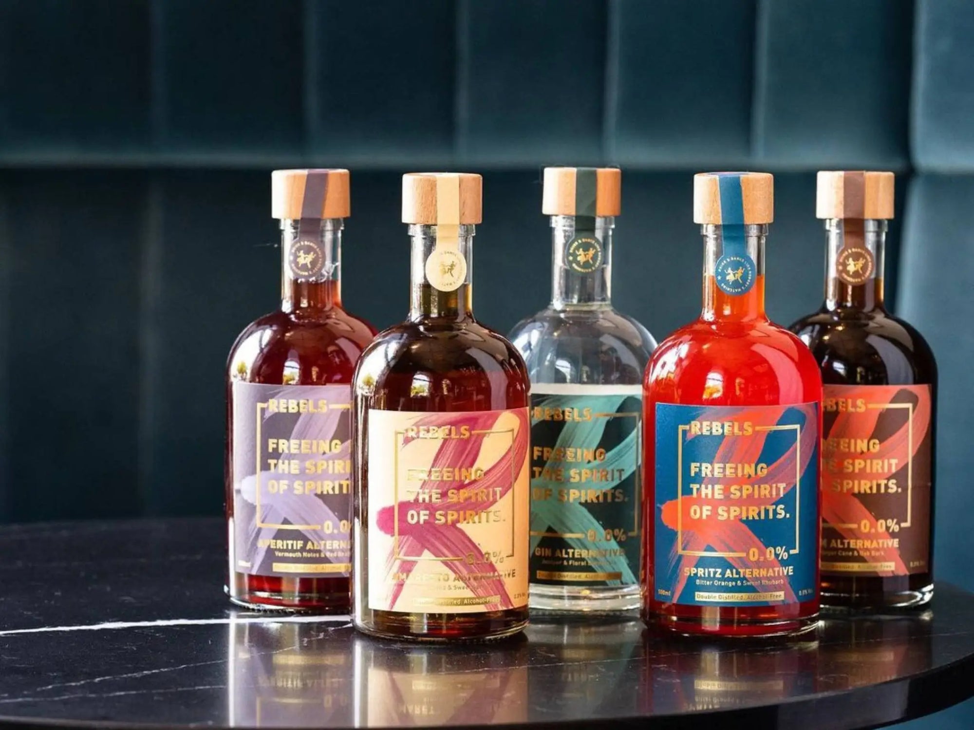 Fünf Flaschen alkoholfreier Rebels-Spirituosen auf einem schwarzen Tisch