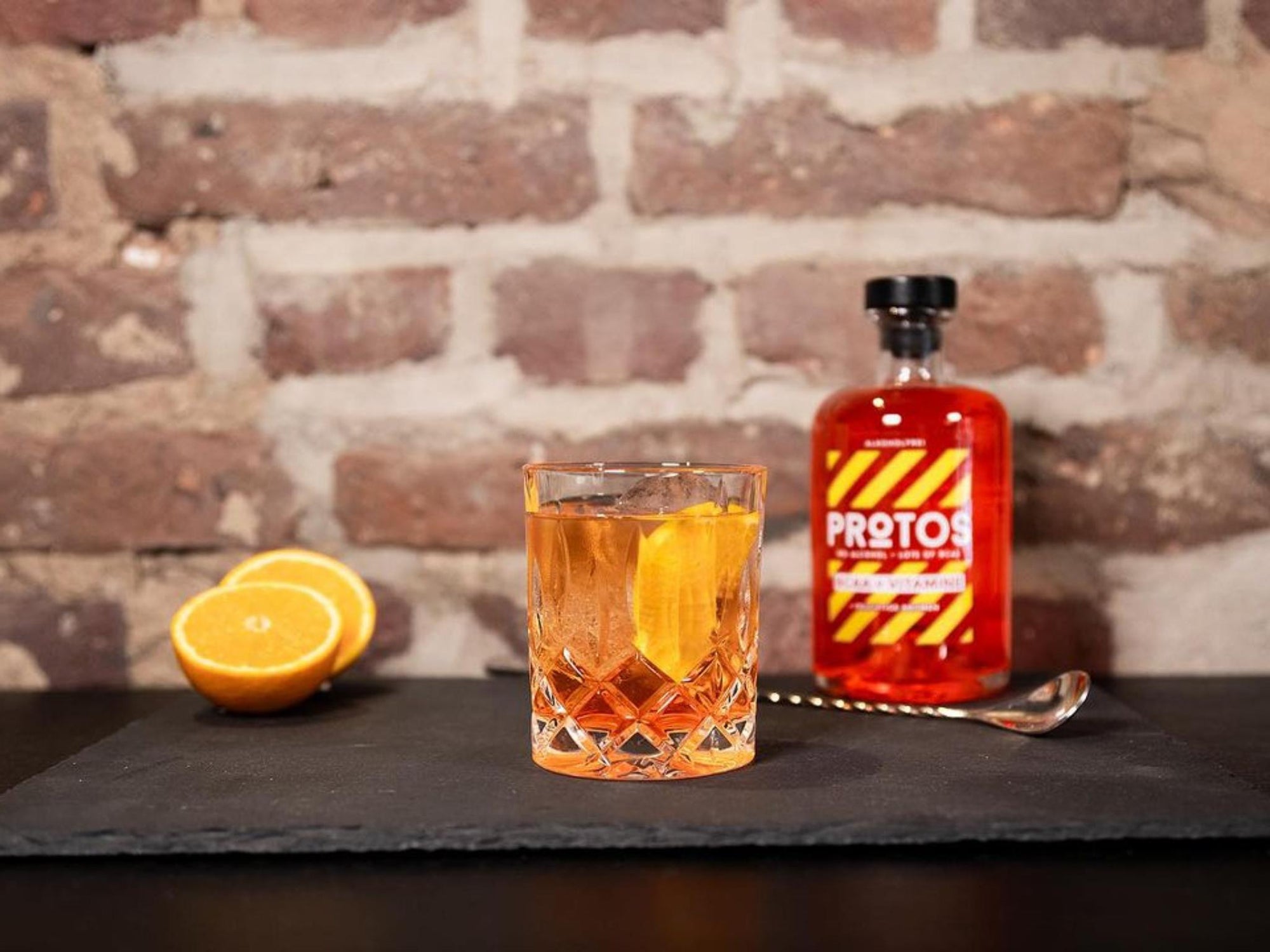 Alkoholfreier Protos-Drink im Glas mit Orangenschale und Flasche