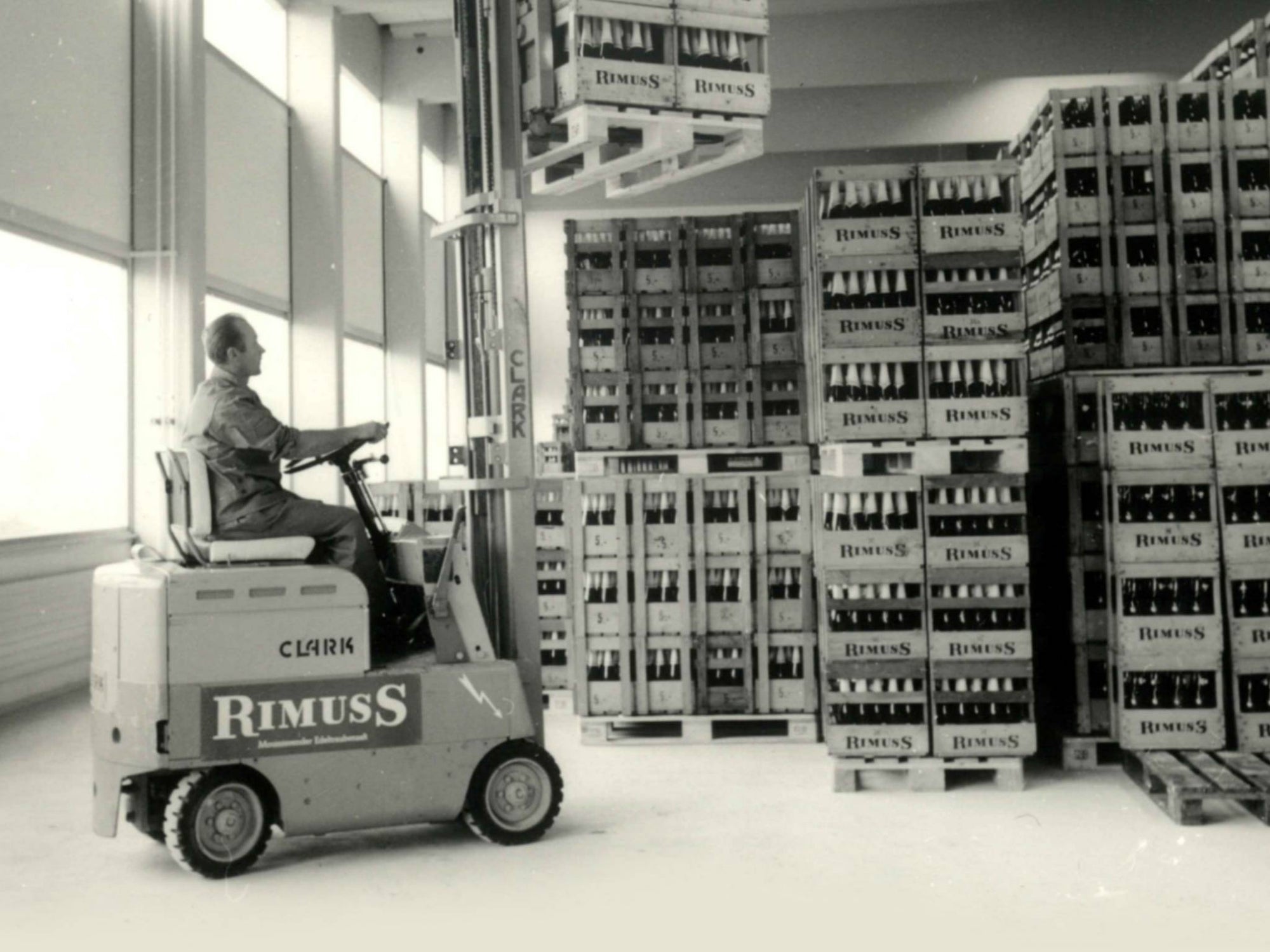 Mann auf Gabelstapler stapelt Kisten mit alkoholfreien Rimuss-Flaschen