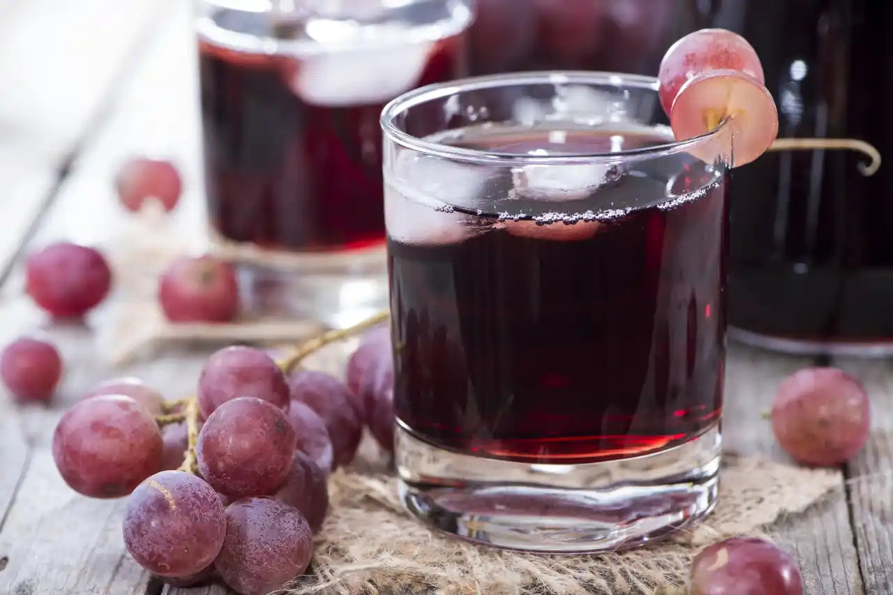 Edeltraubensäfte im Glas mit roten Trauben