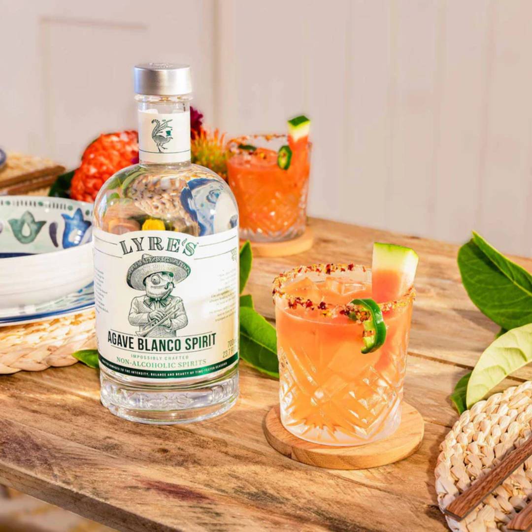 Lyre's Agave Blanco Spirit alkoholfreie Tequila-Alternative mit dekorativem Cocktail auf einem gedeckten Tisch"