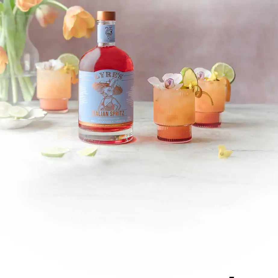 Lyre's Italian Spritz Flasche, umgeben von dekorierten Cocktails und Blumen